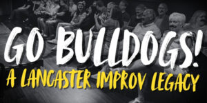 Text reads Go Bulldogs! A Lancaster Improv Legacy. Text is in white and yellow, overlaid on an image of several people seated in the audience at LIP theater most of them are wearing fake mustaches.